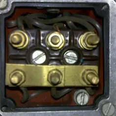 Terminal box of a three-phase motor with wires and brass connectors.
