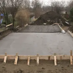 Plac budowy z wylana betonowa płyta fundamentowa, zbrojenie czeka na zalanie. Jaki beton na fundament? Ten wygląda solidnie.
