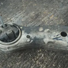 Metalowy pręt włożony w zużyty gumowy element wahacza, przygotowanie do wymiany sworznia wahacza.