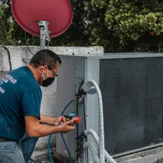 Technik sprawdza czujnik ciśnienia klimatyzacji za pomocą manometru.