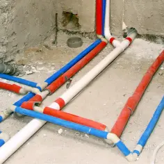 Skomplikowana instalacja hydrauliczna z rurami w kolorach czerwonym, niebieskim i białym. Trudno od razu stwierdzić, z której strony ciepła woda.