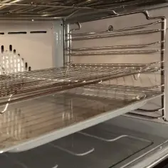 Wnętrze piekarnika z rusztami i blachą, gotowe do czyszczenia katalitycznego.