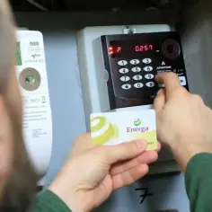 Osoba dokonuje doładowanie licznika przedpłatowego, wkładając kartę Energa i wpisując kod na klawiaturze.