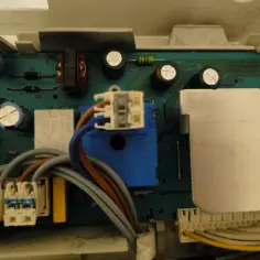 Płyta sterująca pralki Electrolux z błędem E40. Widoczne przekaźniki, kondensatory i złącza kablowe.