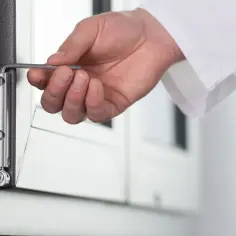 Dłoń z kluczem imbusowym reguluje zawias okna, przygotowując je do trybu zimowego.