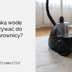 Czarna parownica z przezroczystym zbiornikiem na wodę, stojąca na dywanie.