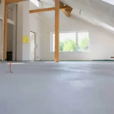 Nowe wnętrze z drewnianymi belkami i oknem. Wylewka betonowa cena za m2 robocizny bez materiału jest kluczowa dla dalszych prac.
