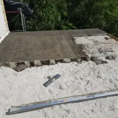Budowa dachu z wykorzystaniem styrobetonu. Widać świeżo wylany materiał i narzędzia do jego obróbki.