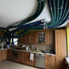 Instalacja rekuperacji w starym domu. W kuchni na suficie widać gęstą plątaninę zielonych i niebieskich rur wentylacyjnych.