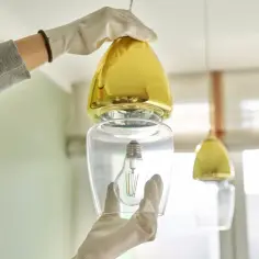 Rękawiczki chronią dłonie podczas wymiany żarówki w ozdobnej lampie.