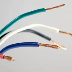 Kilka kolorowych przewodów elektrycznych, w tym zielony, biały, czarny, niebieski i czerwony. Widoczne są miedziane żyły. Jeden z przewodów to przewód neutralny.