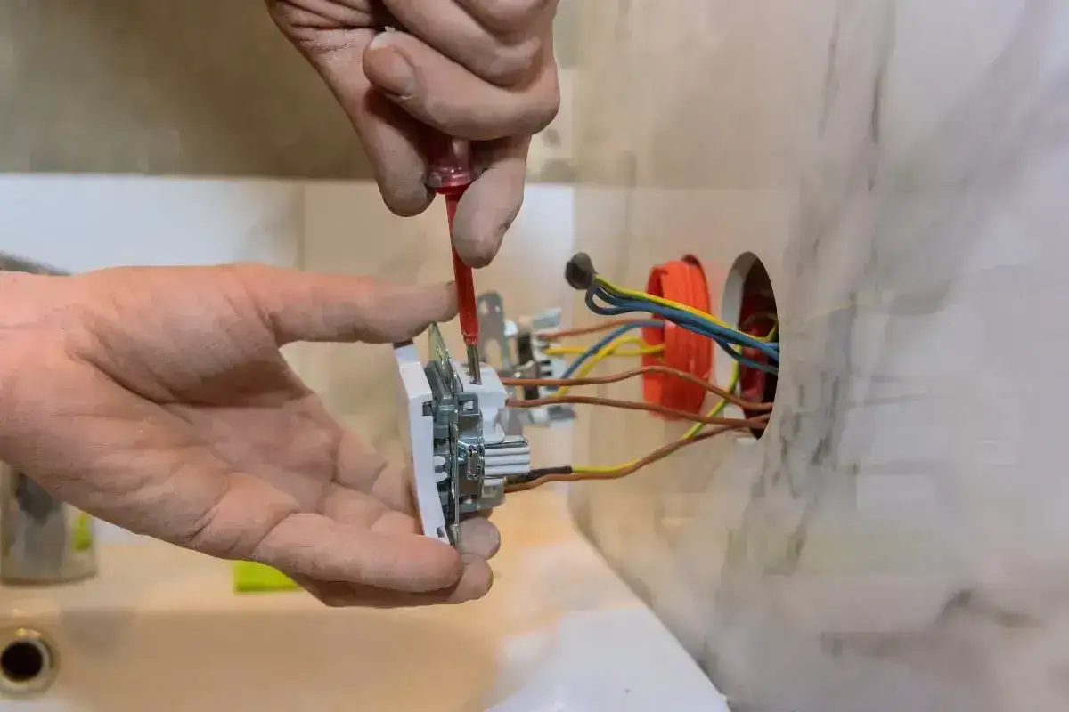 Elektryk montuje gniazdko, podłączając przewody. Dobór odpowiedniego kabla do gniazdek jest kluczowy dla bezpieczeństwa.