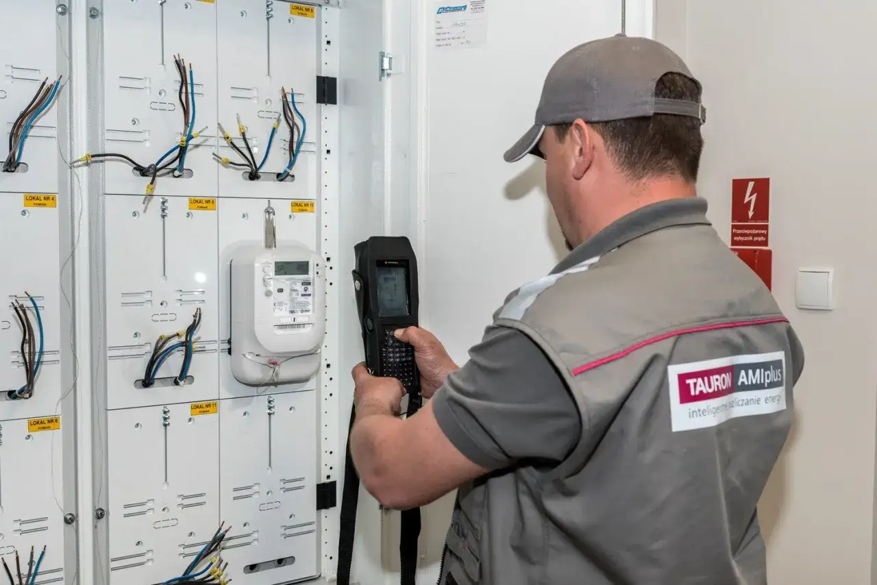 Pracownik Tauron AMIplus dokonuje wymiany licznika. Uważaj na oszustów podszywających się pod pracowników energetyki.